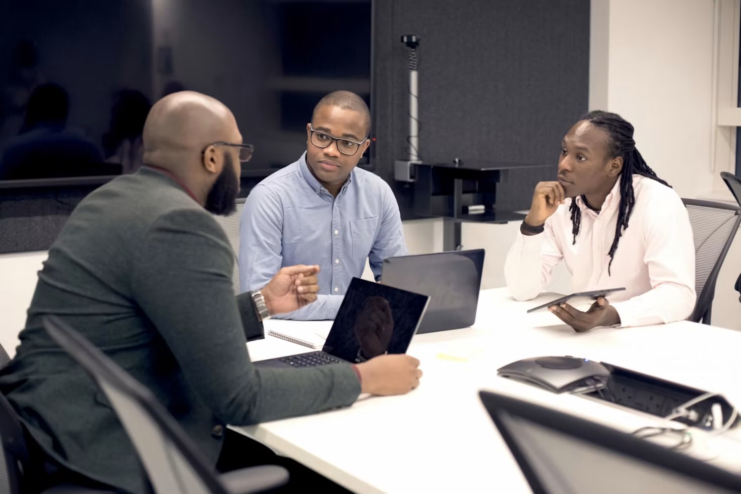 Three Black professionals discussing a business project around a table